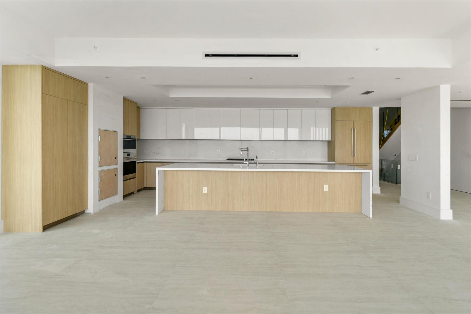 A modern kitchen features light wood cabinetry, white upper cabinets, and a large central island — 12450 SE Crystal Cove Place # 2, Jupiter FL 33469, JUPITER, FL