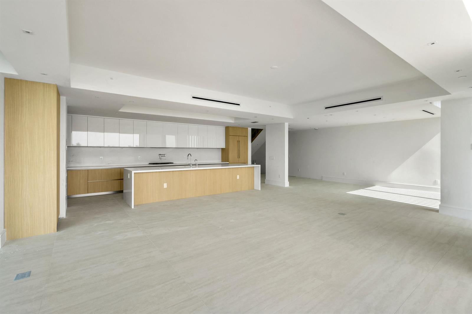A modern kitchen features light wood cabinetry, white upper cabinets, and a large central island — 12450 SE Crystal Cove Place # 2, Jupiter FL 33469, JUPITER, FL
