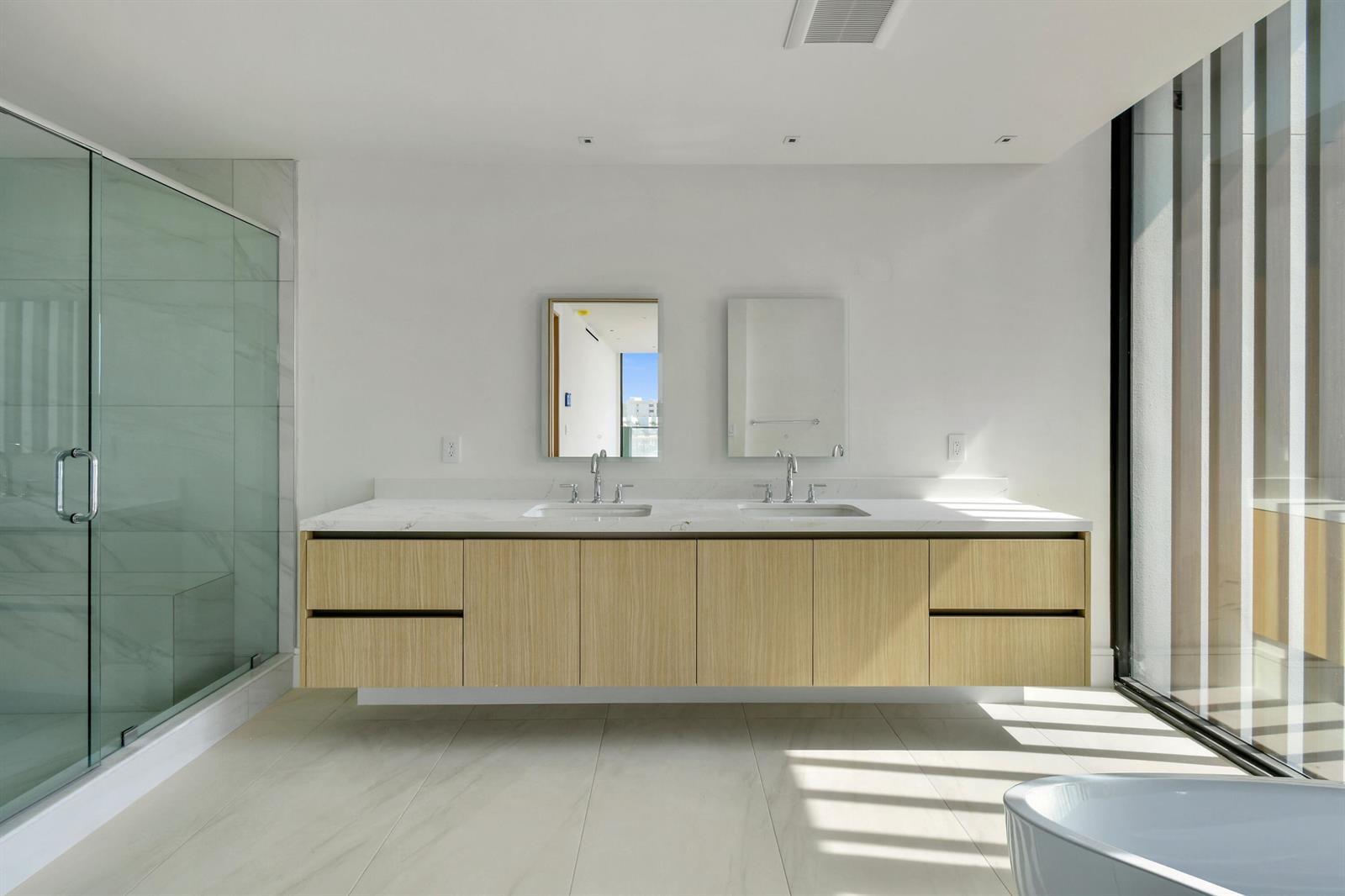 A modern bathroom features a floating wood vanity with double sinks and a glass shower — 12450 SE Crystal Cove Place # 2, Jupiter FL 33469, JUPITER, FL