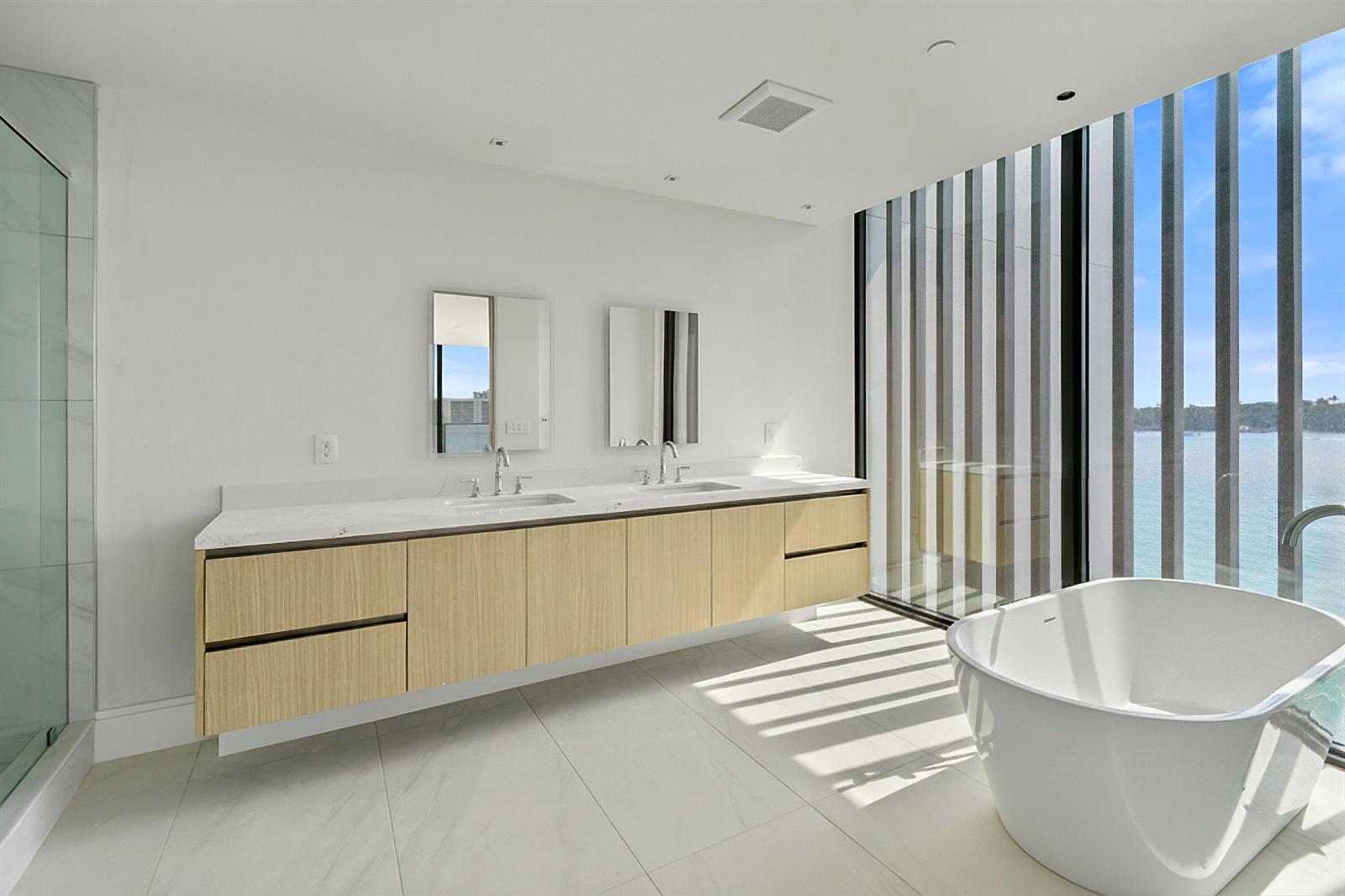 A modern bathroom features a floating wood vanity, dual sinks, and a freestanding soaking tub — 12450 SE Crystal Cove Place # 2, Jupiter FL 33469, JUPITER, FL