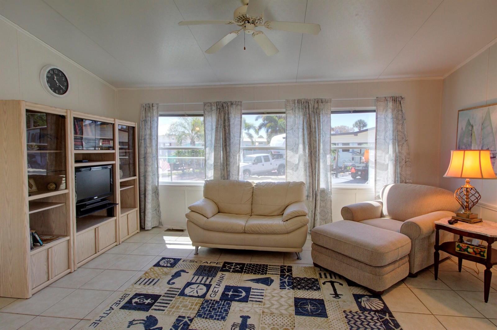 A living room features a white sofa, an armchair with an ottoman, and a nautical rug — 5395 SE 64th Terrace, Okeechobee FL 34974, OKEECHOBEE, FL