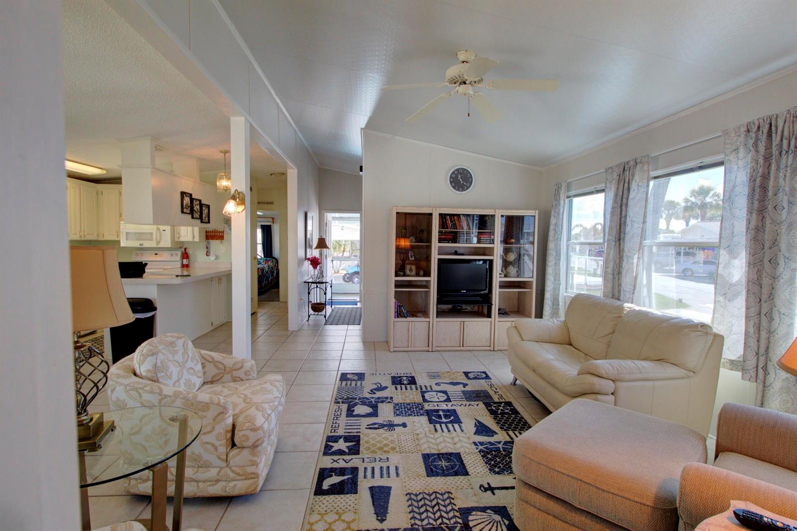 A living room with tile floors, a ceiling fan, and a nautical-themed area rug — 5395 SE 64th Terrace, Okeechobee FL 34974, OKEECHOBEE, FL