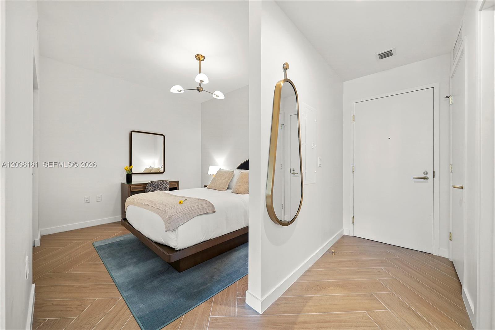 A bedroom with a platform bed and a modern mirror is visible from a hallway — 2700 NW 2nd Ave # 532, Miami FL 33127, MIAMI, FL