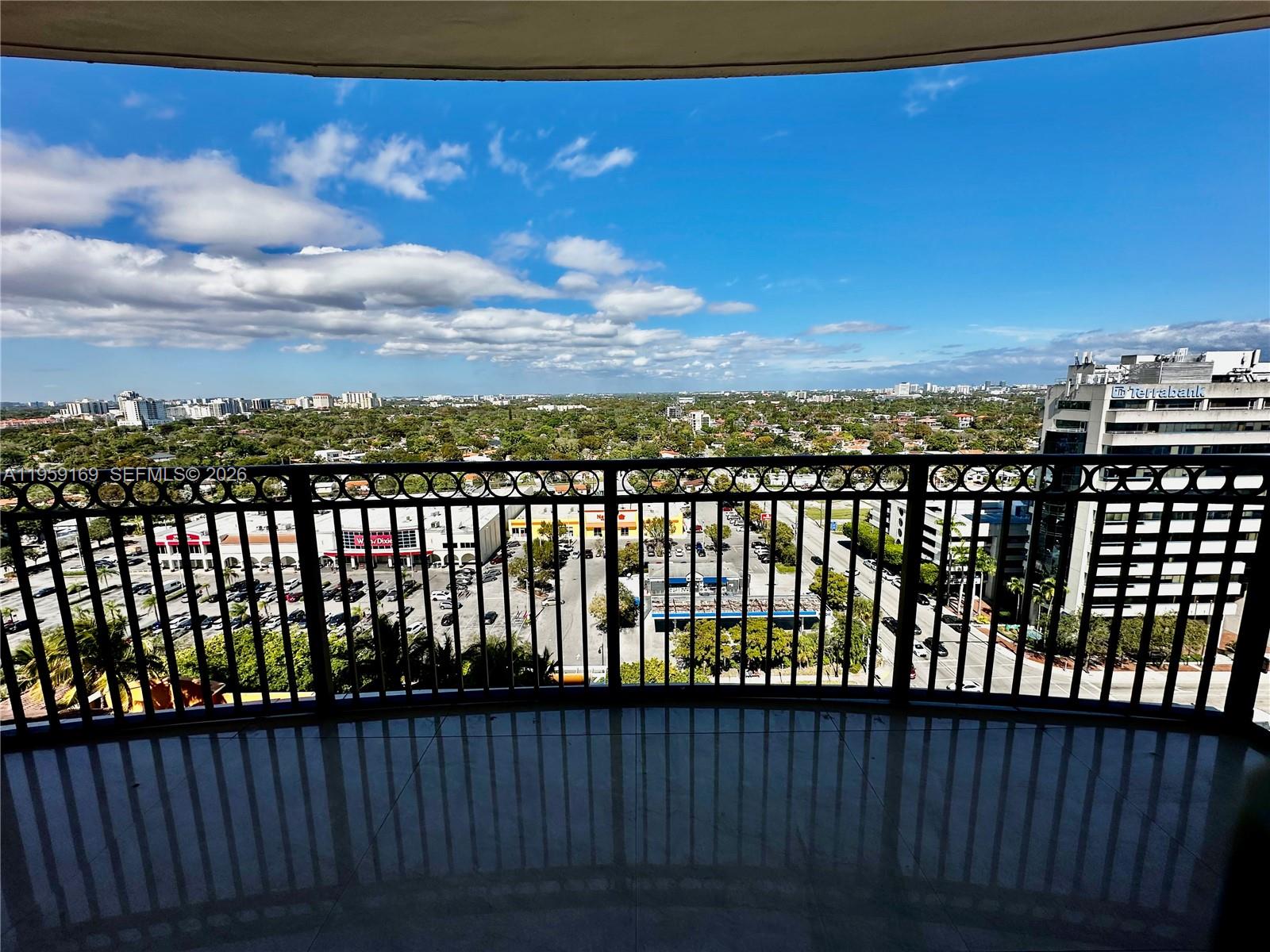 A balcony with a black metal railing overlooks a parking lot and city skyline — 3232 SW 22nd Ter # 1604, Miami FL 33145, MIAMI, FL
