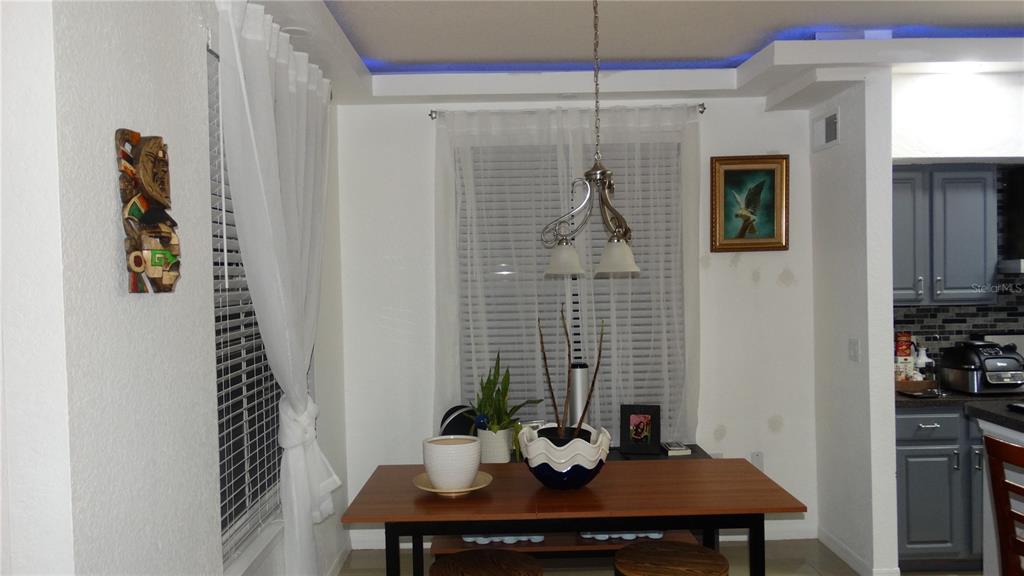 A dining area features a wooden table, a pendant light, and blue tray ceiling lighting — 5957 WESTGATE DRIVE UNIT 1914, ORLANDO, FL