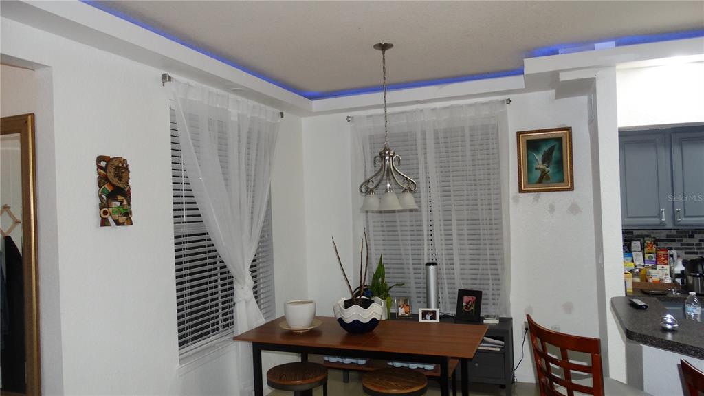 A dining area features a wooden table, pendant lighting, blue tray ceiling accents, and windows — 5957 WESTGATE DRIVE UNIT 1914, ORLANDO, FL