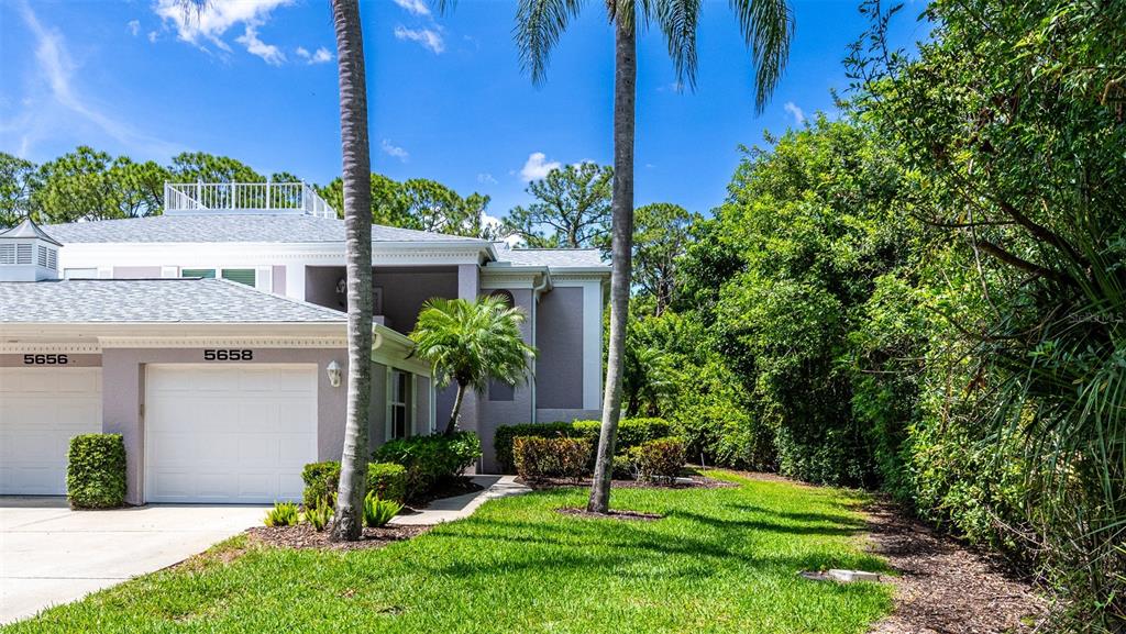 A two-story residential building features a white garage, palm trees, and a grassy lawn — 5658 SHEFFIELD GREENE CIRCLE UNIT 66-17, SARASOTA, FL