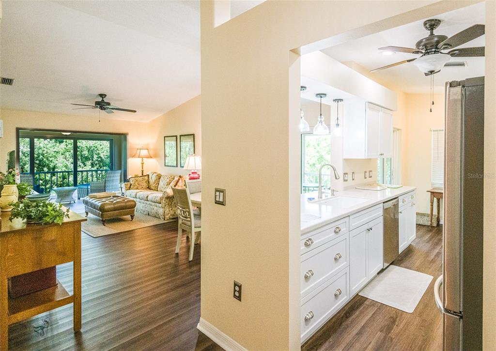 A view from a kitchen looking into a living room with wood-look flooring — 5658 SHEFFIELD GREENE CIRCLE UNIT 66-17, SARASOTA, FL