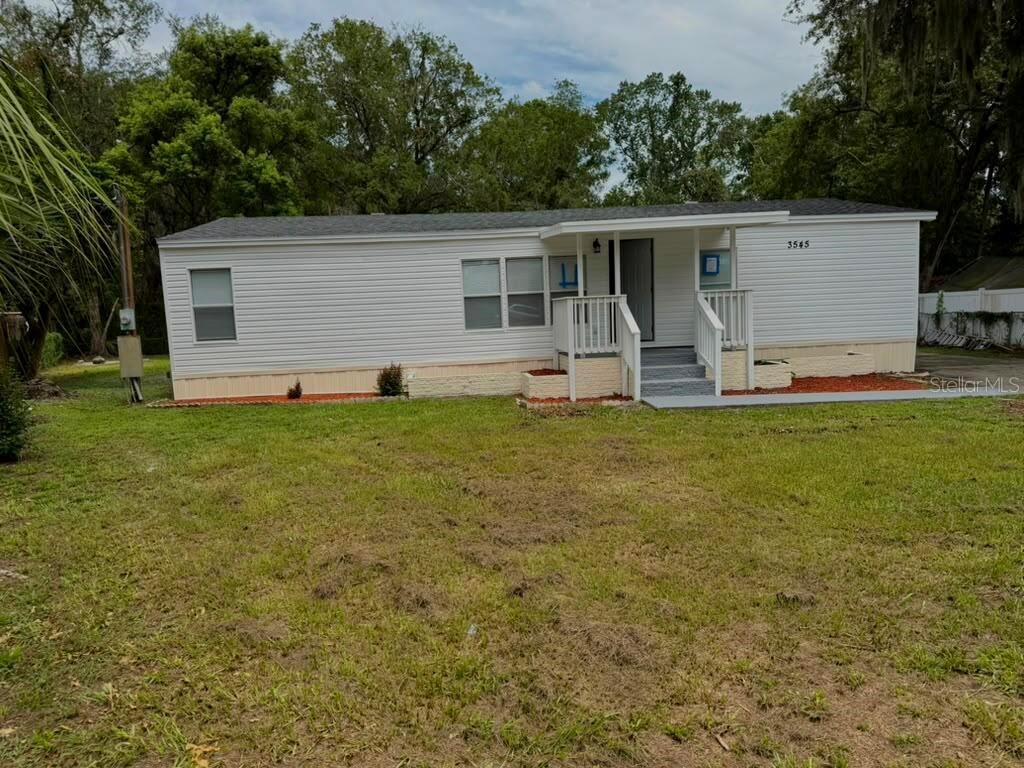 A single-story manufactured home with white siding, a covered porch, and a grassy yard — 3545 SHADY BROOKE COURT, MULBERRY, FL