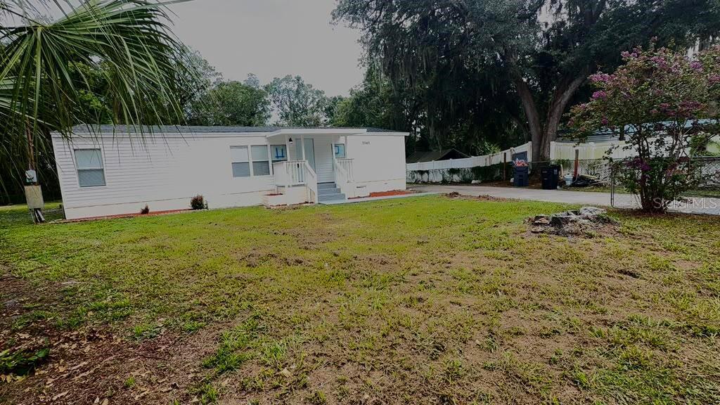 A white manufactured home sits on a grassy lot with a tree stump in front — 3545 SHADY BROOKE COURT, MULBERRY, FL