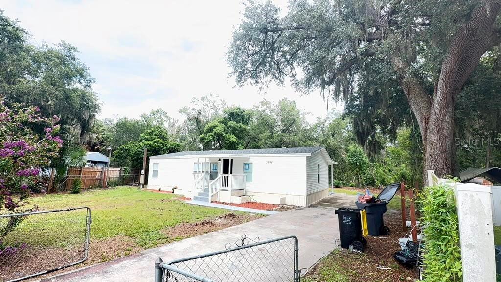 A white single-story manufactured home sits on a grassy lot with a concrete driveway — 3545 SHADY BROOKE COURT, MULBERRY, FL