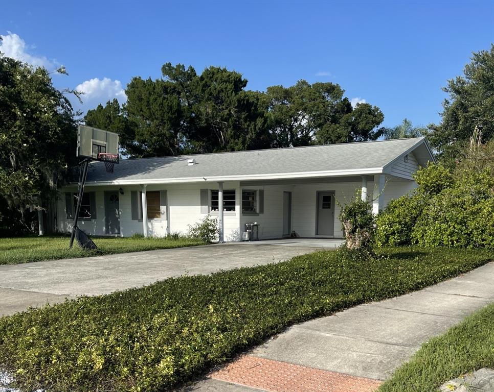 A single-story white house with a gray roof, a carport, and a basketball hoop — 437 CAROLINA AVENUE, ST CLOUD, FL