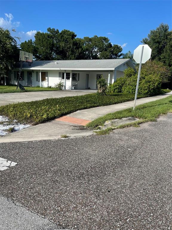 A single-story white house with a carport sits behind a sidewalk and a stop sign — 437 CAROLINA AVENUE, ST CLOUD, FL