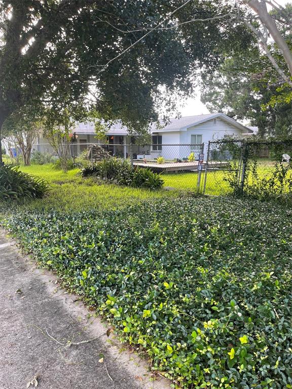 A white house with a chain-link fence and a wooden deck in the front yard — 437 CAROLINA AVENUE, ST CLOUD, FL