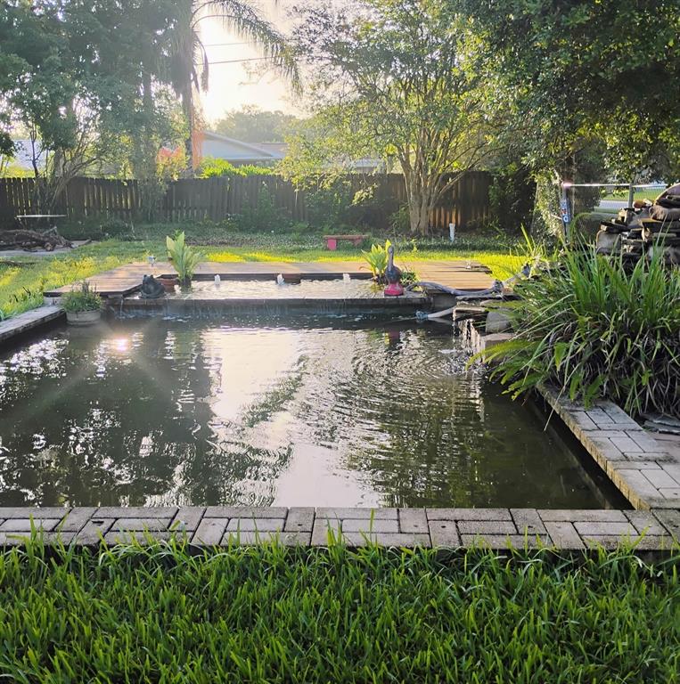 A rectangular backyard pond features a tiered water feature, wooden decking, and brick paver edging — 437 CAROLINA AVENUE, ST CLOUD, FL