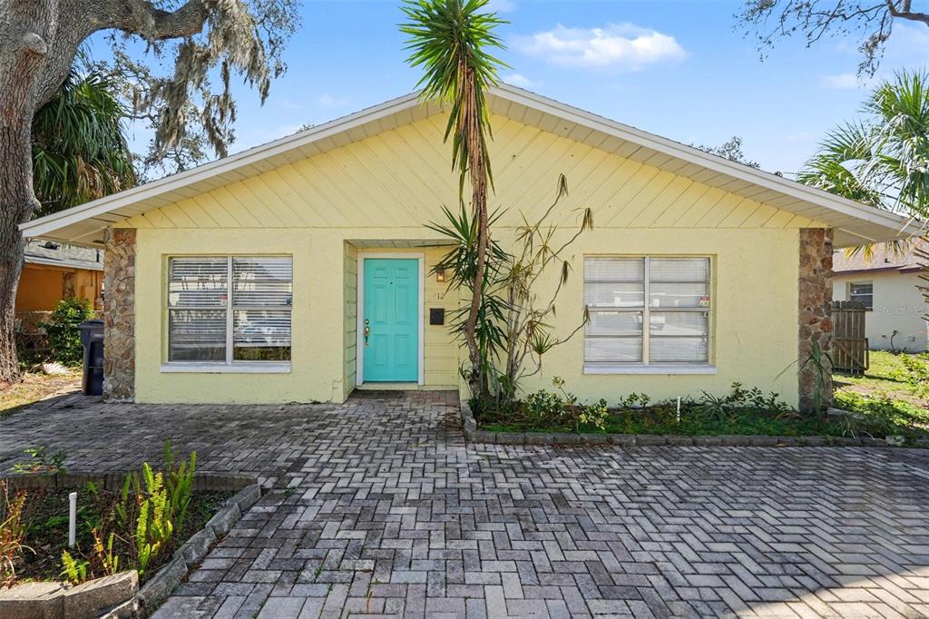 A yellow single-story house with a turquoise front door and a paved driveway — 412 W IDLEWILD AVENUE, TAMPA, FL
