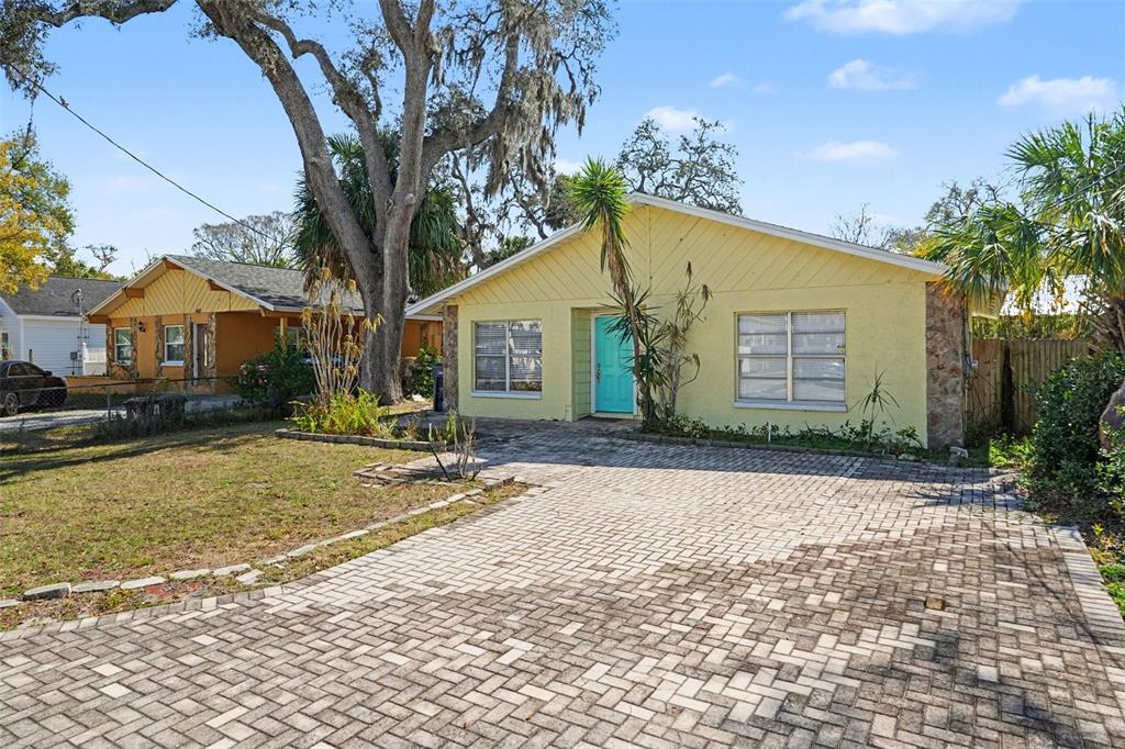 A yellow single-story house with a paved driveway and a bright blue front door — 412 W IDLEWILD AVENUE, TAMPA, FL