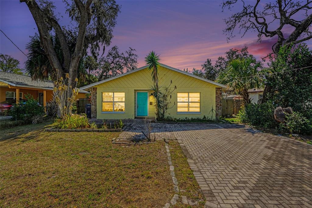 A yellow single-story house with a turquoise front door and a brick paver driveway — 412 W IDLEWILD AVENUE, TAMPA, FL