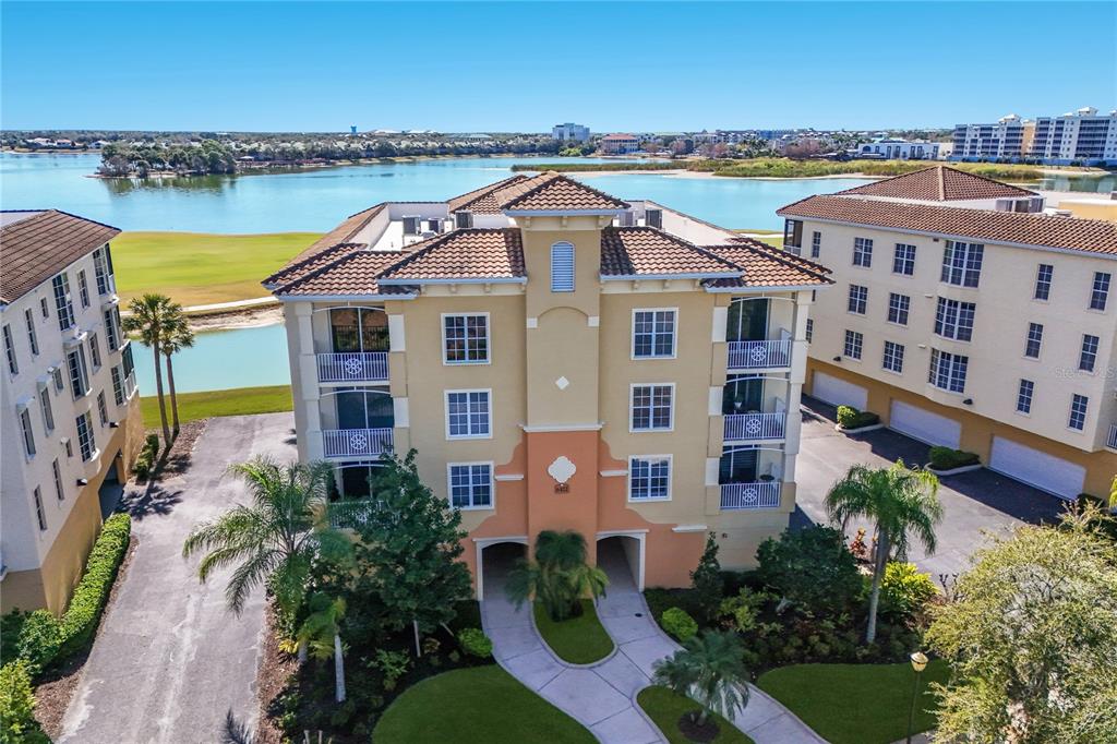 An aerial view of a multi-story apartment building with a tile roof near a lake — 6422 WATERCREST WAY UNIT 302, LAKEWOOD RANCH, FL