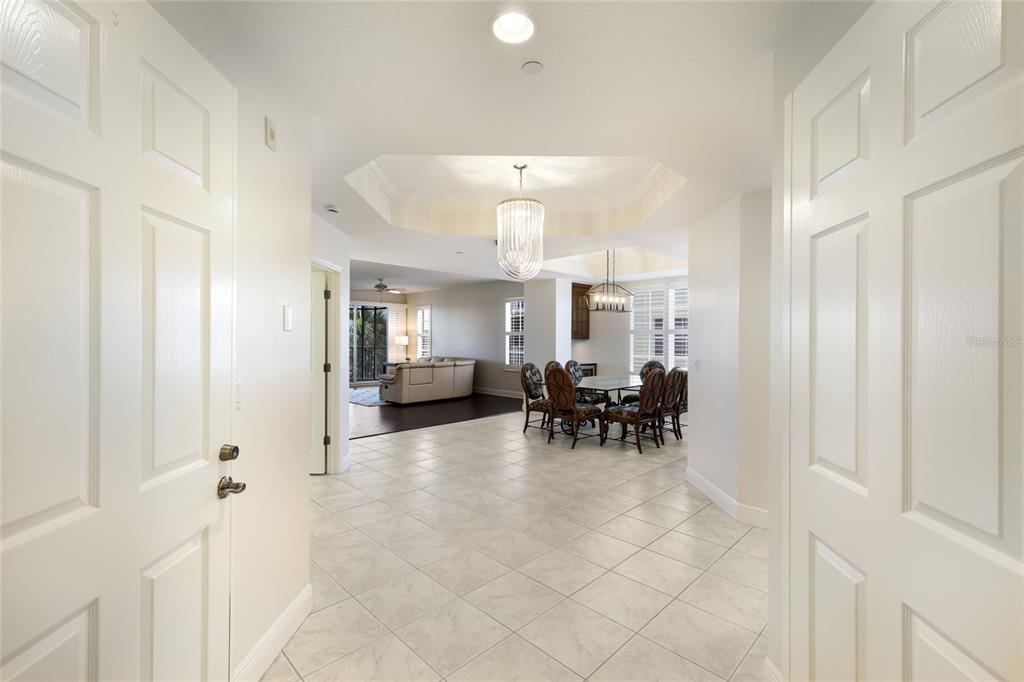 A view from a doorway into a tiled foyer, dining area, and living room — 6422 WATERCREST WAY UNIT 302, LAKEWOOD RANCH, FL