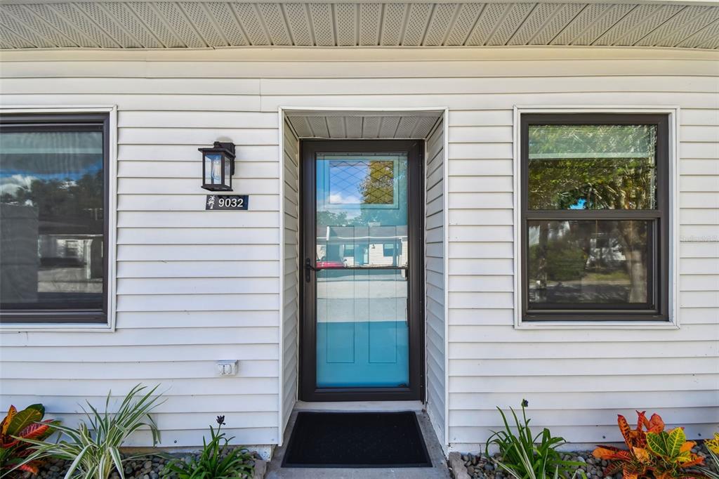 The exterior of a house features white horizontal siding, a front door, and two windows — 9032 MISSION OAKS BOULEVARD UNIT F, SEMINOLE, FL