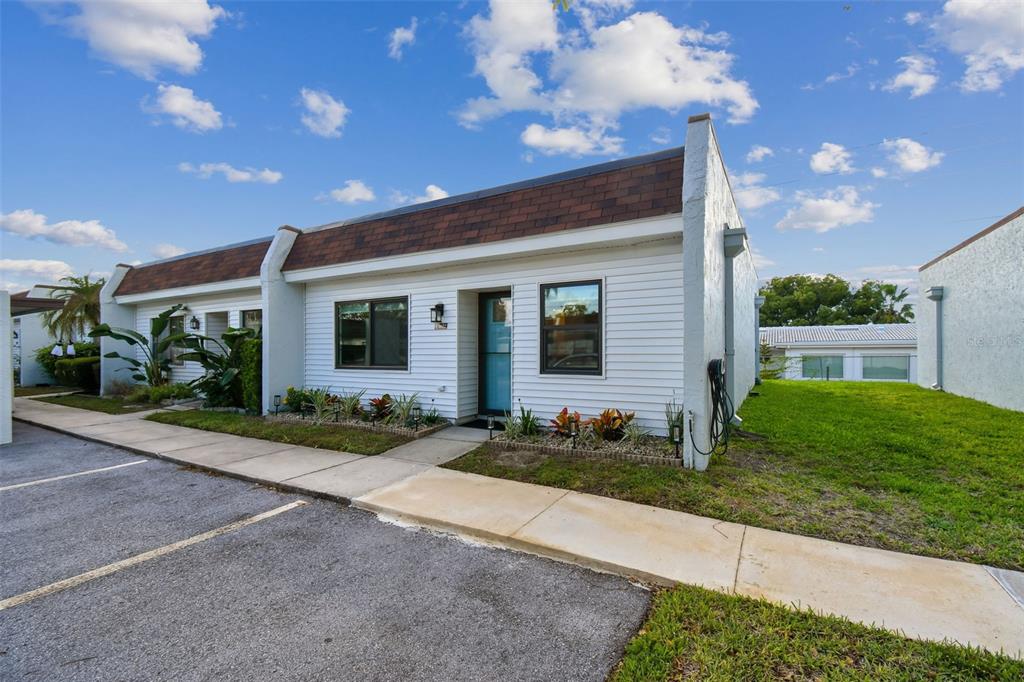A single-story white house with a brown shingled roof and a paved parking area — 9032 MISSION OAKS BOULEVARD UNIT F, SEMINOLE, FL