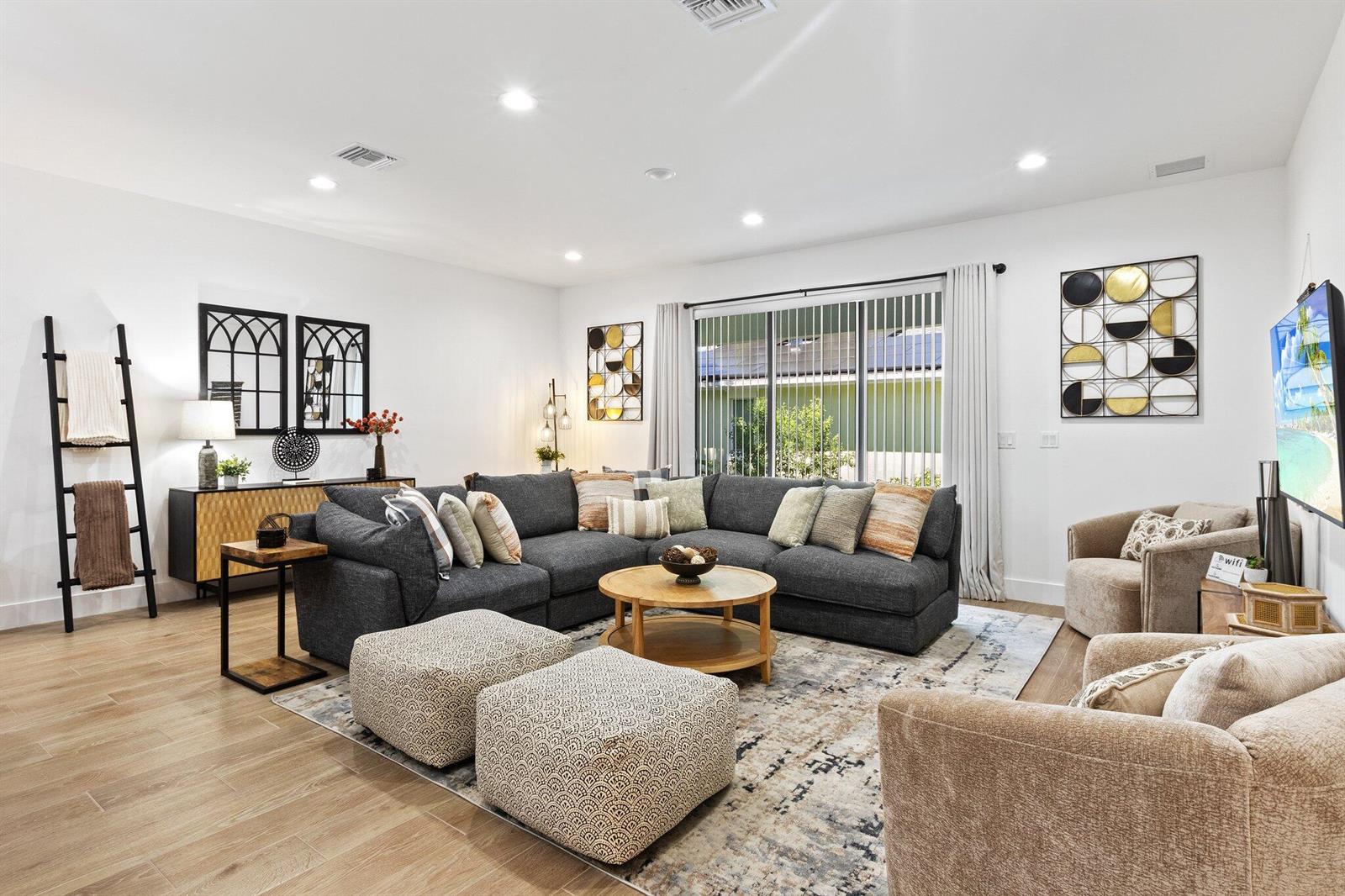 A living room features a large gray sectional, two patterned ottomans, and a round coffee table — 601 SW 3rd Street, Delray Beach FL 33444, DELRAY BEACH, FL