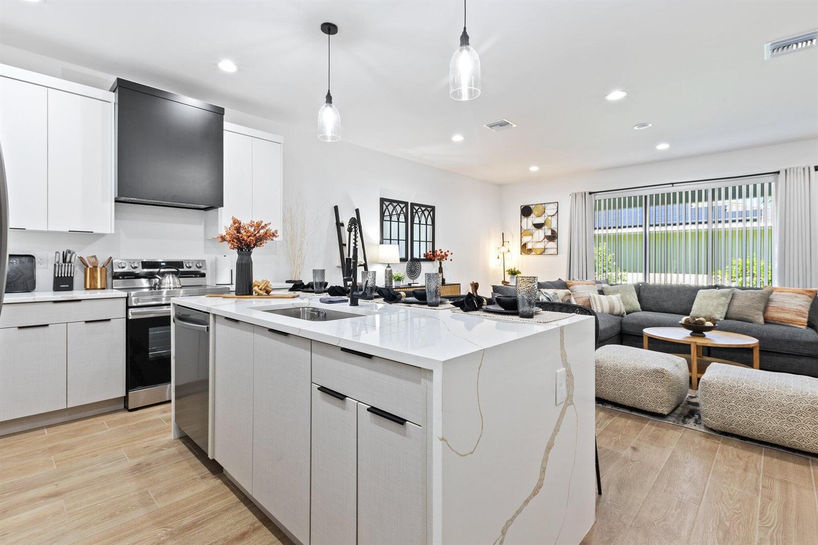 A modern kitchen with a white quartz island and black range hood overlooks a living area — 601 SW 3rd Street, Delray Beach FL 33444, DELRAY BEACH, FL
