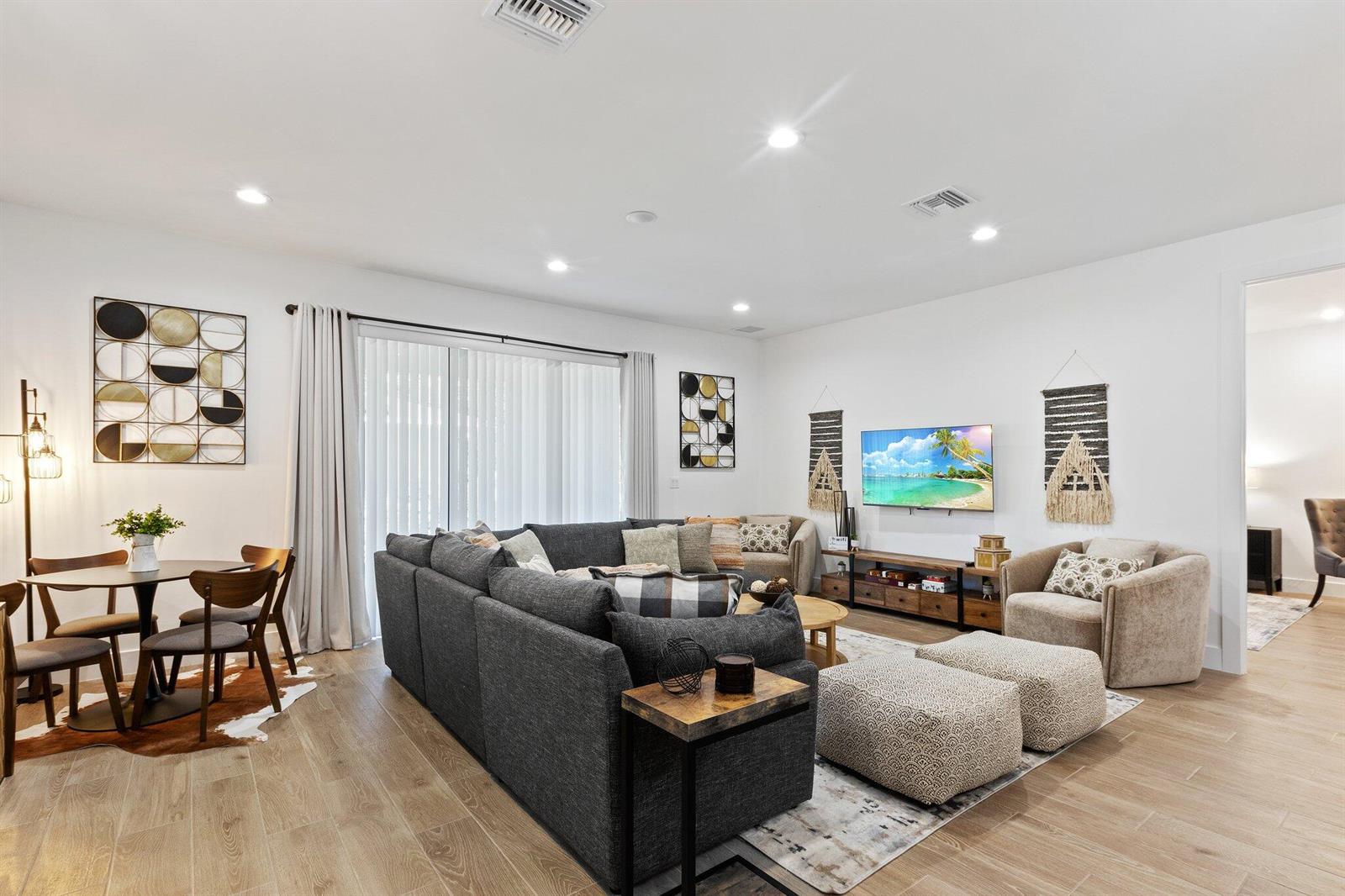 A living room features a large gray sectional, dining area, and wall-mounted television — 601 SW 3rd Street, Delray Beach FL 33444, DELRAY BEACH, FL
