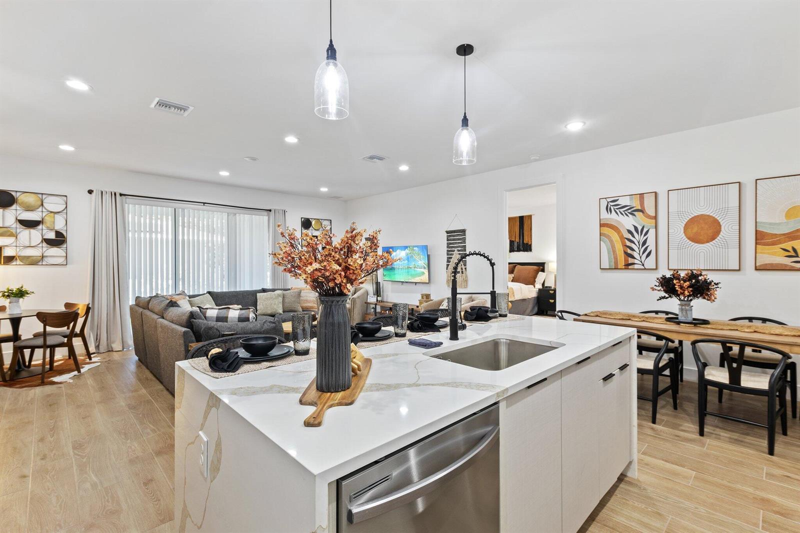 A modern kitchen island with a white countertop overlooks an open-concept living and dining area — 601 SW 3rd Street, Delray Beach FL 33444, DELRAY BEACH, FL