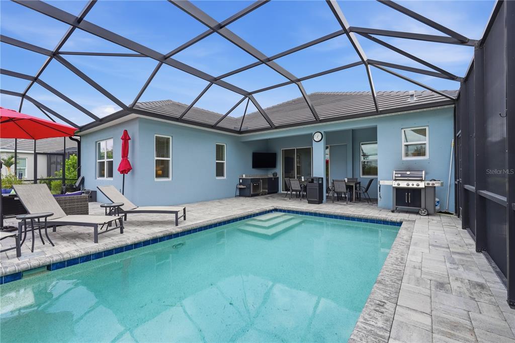A swimming pool with a screened-in patio, outdoor kitchen, and lounge chairs — 12950 SEASONG TERRACE, BRADENTON, FL