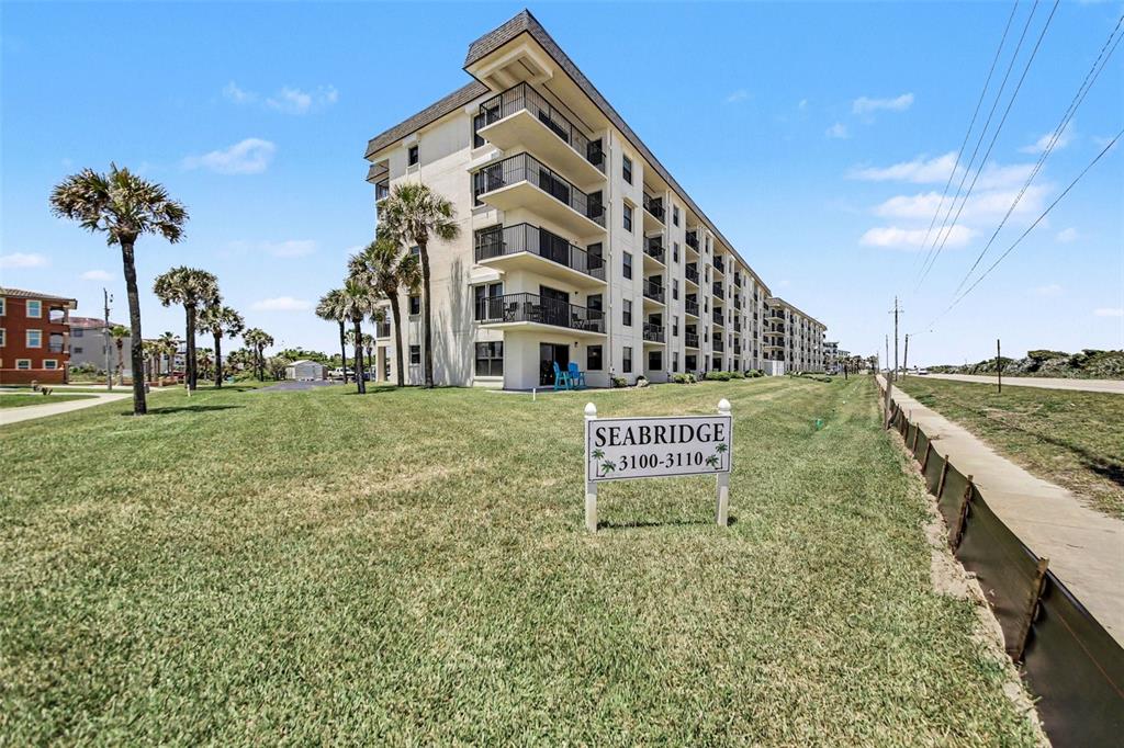 A multi-story residential building stands behind a sign on a grassy lawn — 3100 OCEAN SHORE BOULEVARD UNIT 101, ORMOND BEACH, FL