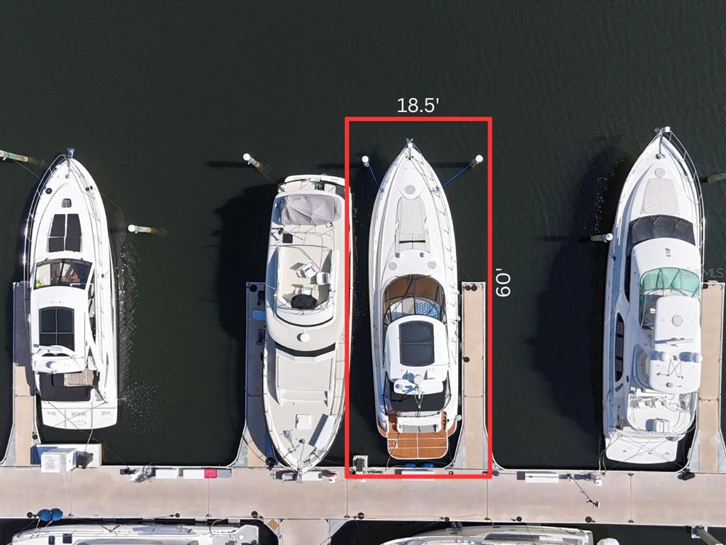 An aerial view shows a boat docked in a slip measuring 18.5 feet by 60 feet — 102 RIVIERA DUNES WAY UNIT S-21, PALMETTO, FL