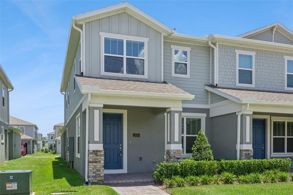 A two-story townhouse with a blue front door, stone accents, and a small front porch — 13253 PEACEFUL MELODY DRIVE, WINTER GARDEN, FL