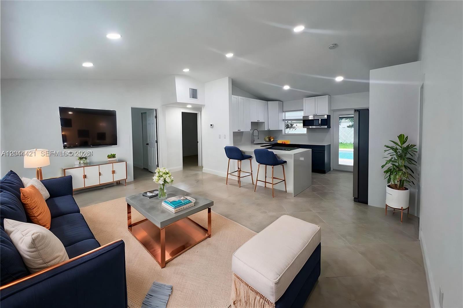 An open-concept living room and kitchen feature white cabinetry, a kitchen island, and tile flooring — 2679 NW 57th Ter, Margate FL 33063, MARGATE, FL