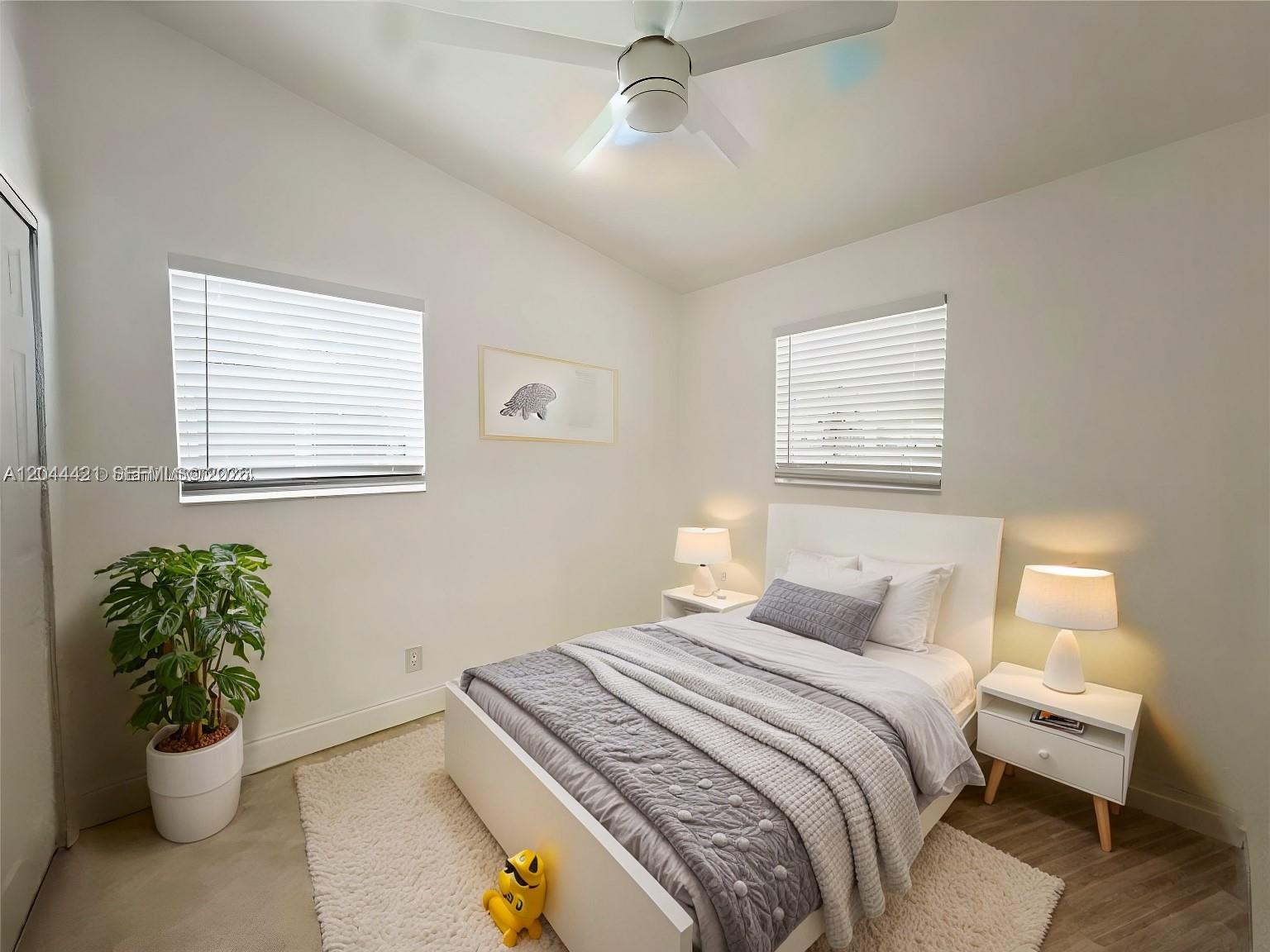 A bedroom features a white bed, two nightstands with lamps, and a potted plant — 2679 NW 57th Ter, Margate FL 33063, MARGATE, FL