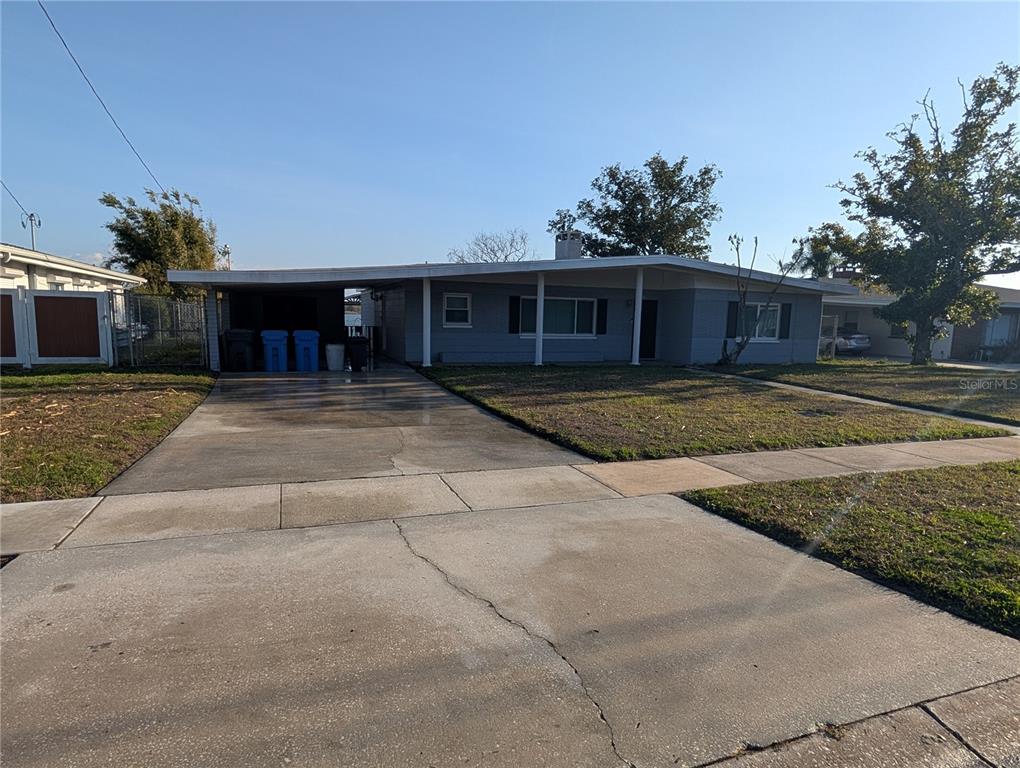 A single-story gray house features a flat roof, a carport, and a concrete driveway — 6517 WALTON WAY, TAMPA, FL