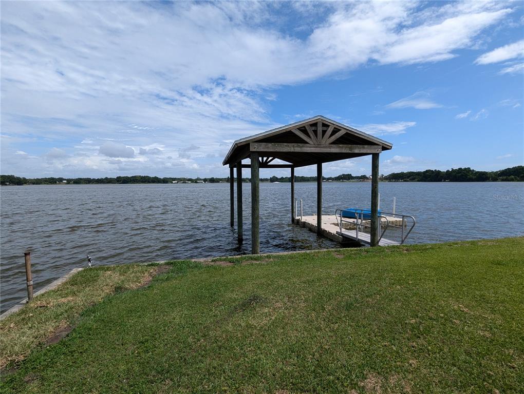 A wooden boat dock with a roof extends into a lake from a grassy lawn — 6517 WALTON WAY, TAMPA, FL