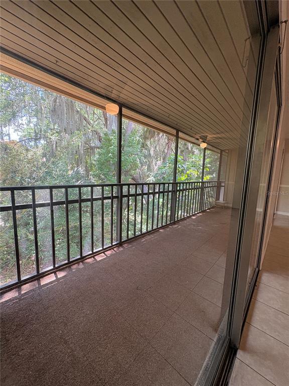 A screened-in balcony with a metal railing overlooks a wooded area with hanging moss — 140 ORCHID WOODS COURT UNIT 7D, DELTONA, FL