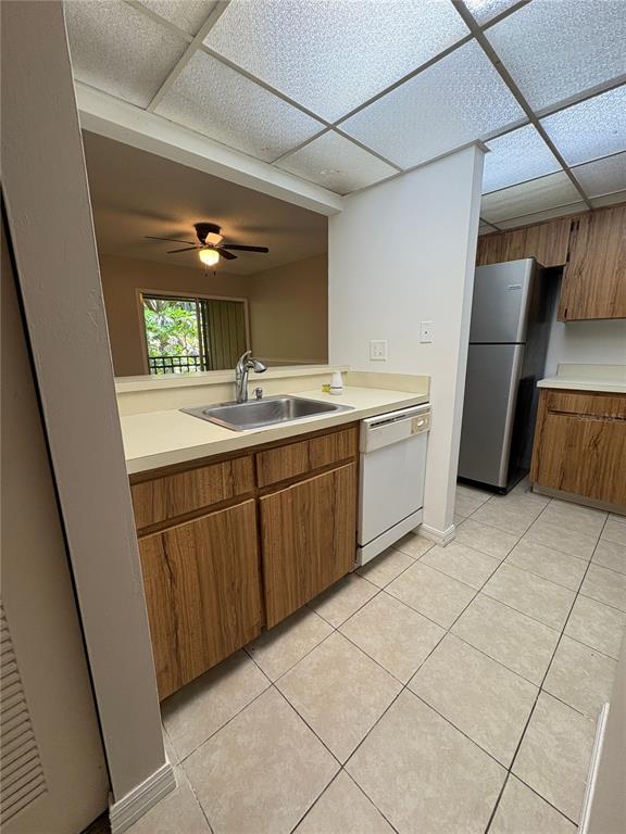 A kitchen features wood-grain cabinets, a stainless steel sink, a dishwasher, and tile flooring — 140 ORCHID WOODS COURT UNIT 7D, DELTONA, FL