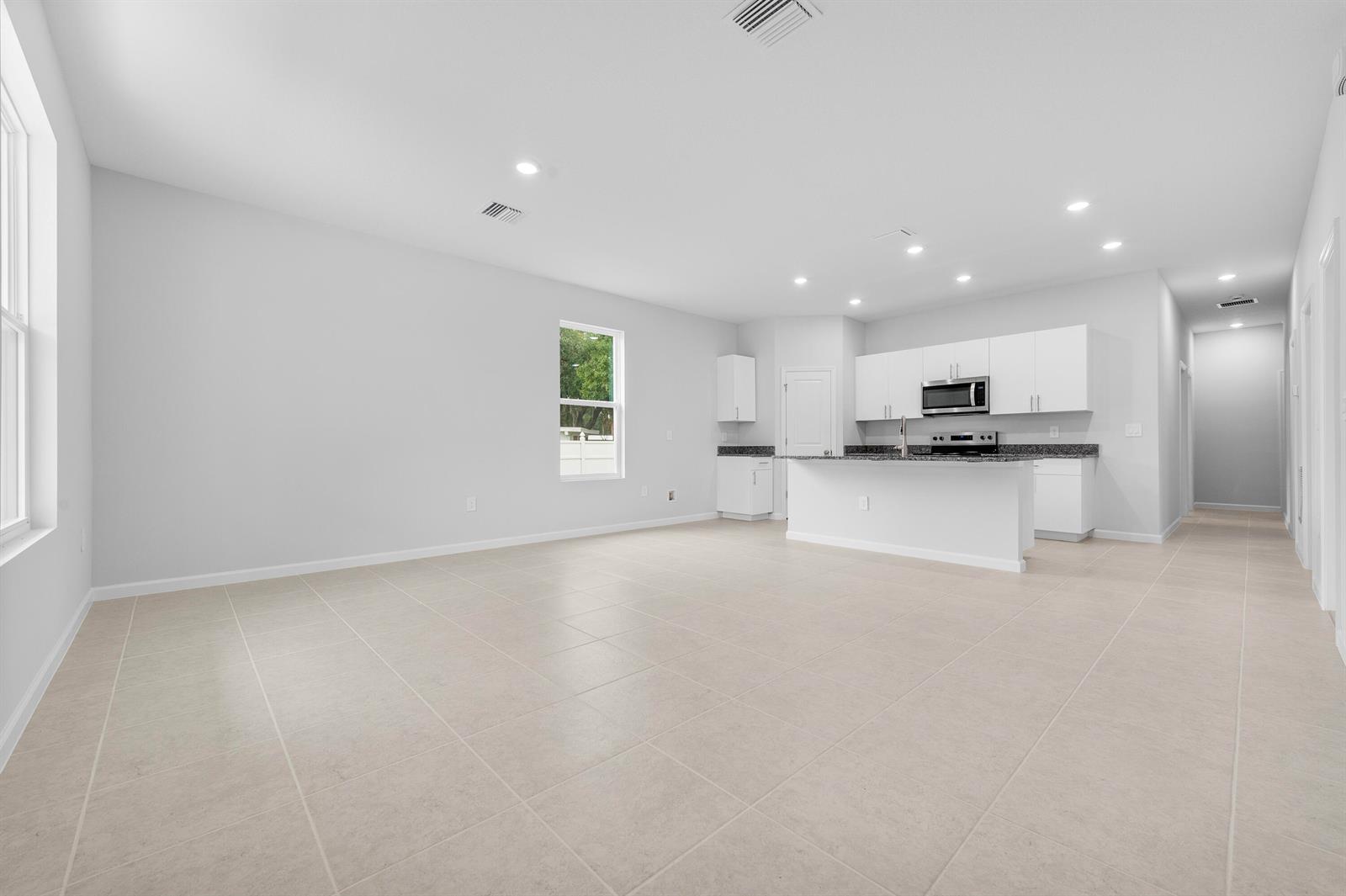 An open-concept kitchen and living area features white cabinets, granite countertops, and tile flooring — 3344 N Park Drive, Fort Pierce FL 34982, FORT PIERCE, FL