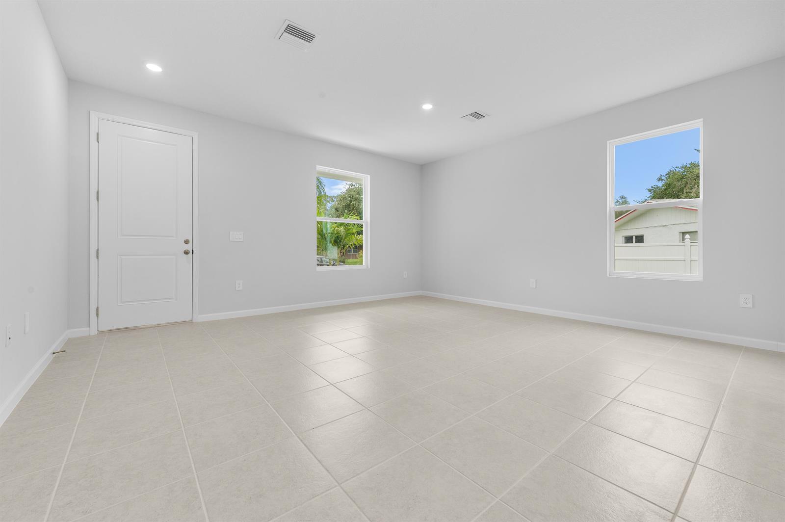 An empty room features light-colored tile flooring, white walls, a door, and two windows — 3344 N Park Drive, Fort Pierce FL 34982, FORT PIERCE, FL