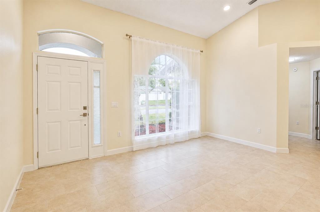 A bright entryway features light tile floors, a white front door, and a large arched window — 2229 FOGGY RIDGE PARKWAY, LAND O LAKES, FL