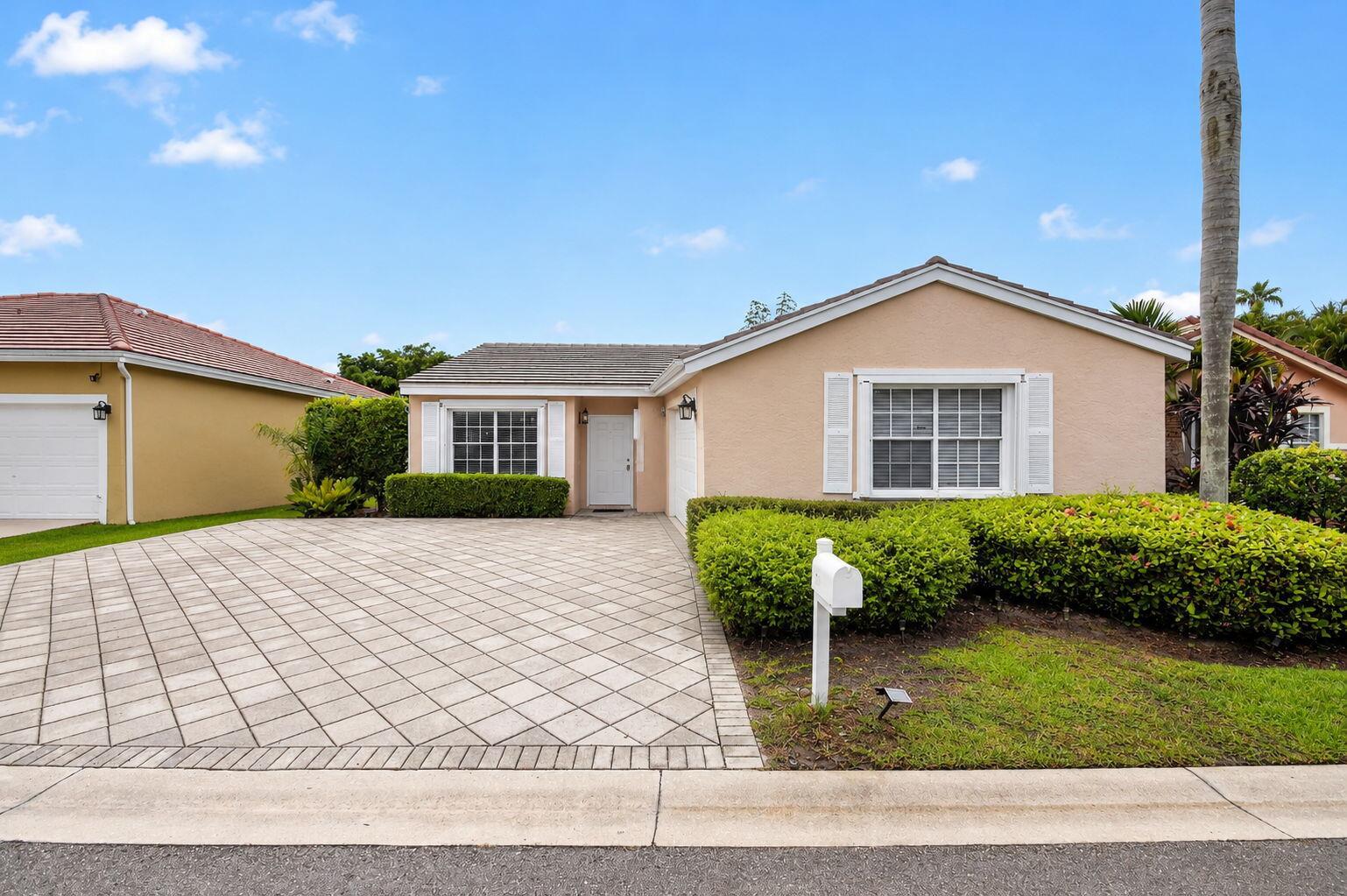 A single-story house with a paved driveway, tan stucco exterior, and manicured landscaping — 208 Caribe Court, FL 33413, FL