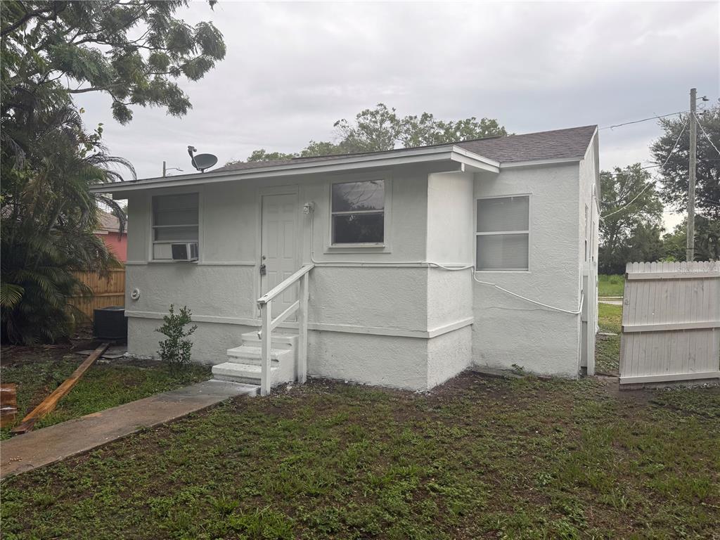 A small, white, single-story house with a front porch and a white wooden fence — 2615 E 28TH AVENUE, TAMPA, FL