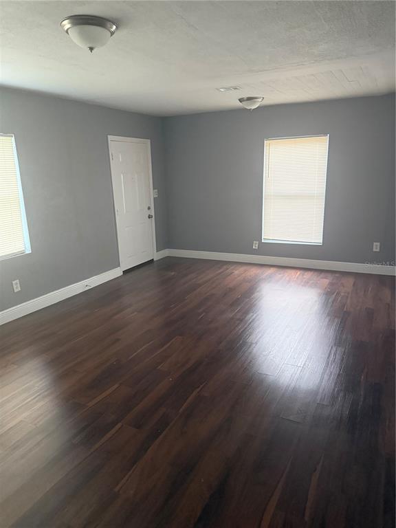 An empty room features gray walls, dark wood flooring, two windows, and two ceiling lights — 2615 E 28TH AVENUE, TAMPA, FL