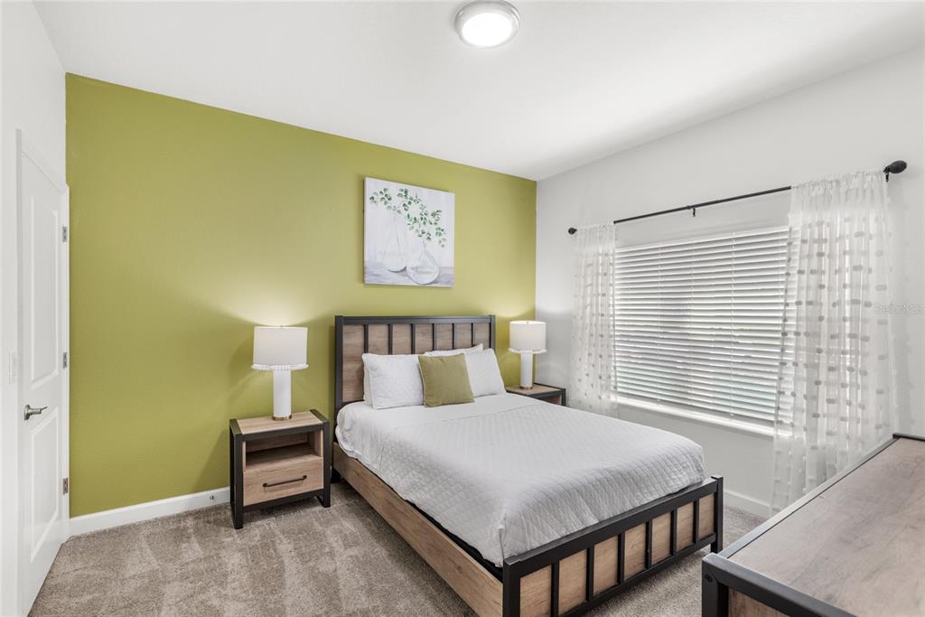 A bedroom features a green accent wall, a metal-framed bed, and a window with curtains — 790 PEBBLE BEACH DRIVE, DAVENPORT, FL