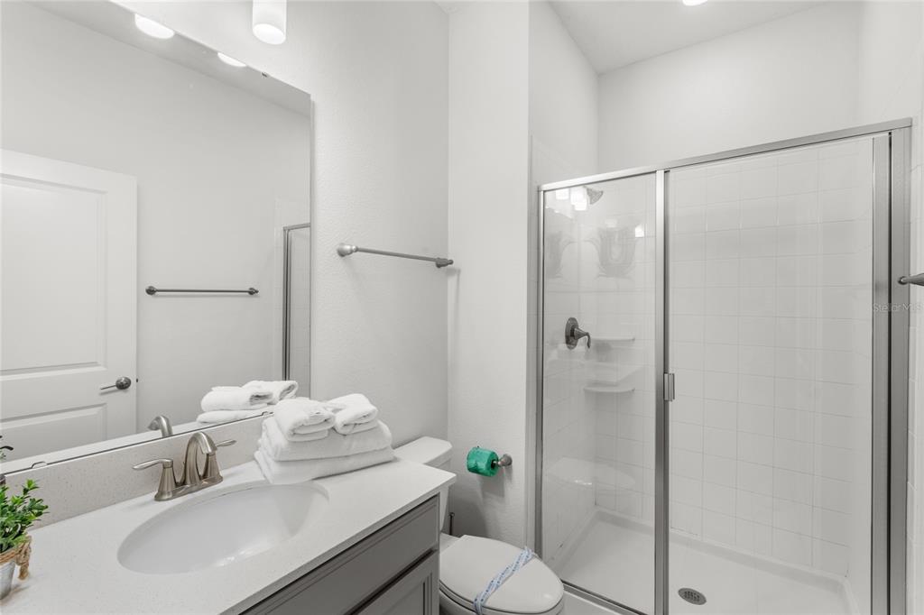 A bathroom features a gray vanity, a white countertop, a mirror, and a glass-enclosed shower — 790 PEBBLE BEACH DRIVE, DAVENPORT, FL