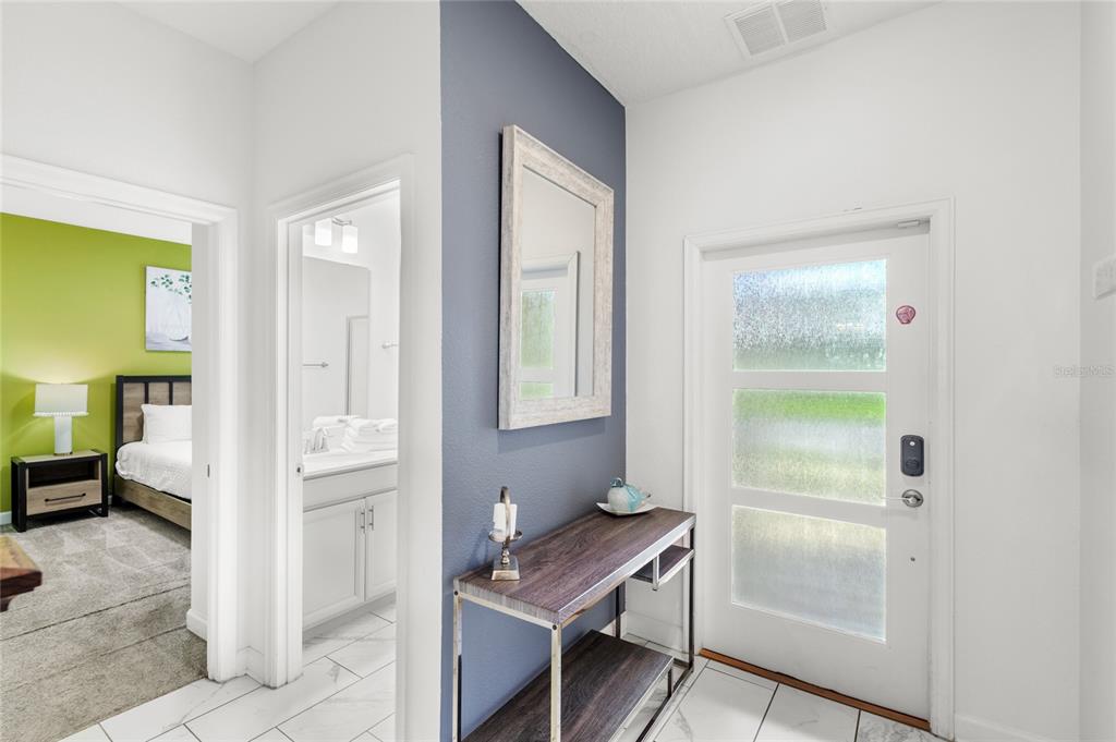 An entryway features a white door, a dark blue accent wall with a mirror, and console — 790 PEBBLE BEACH DRIVE, DAVENPORT, FL