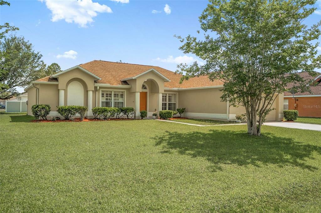 A single-story beige house with a tan shingled roof and a large front lawn — 1 ETHAN PL, PALM COAST, FL